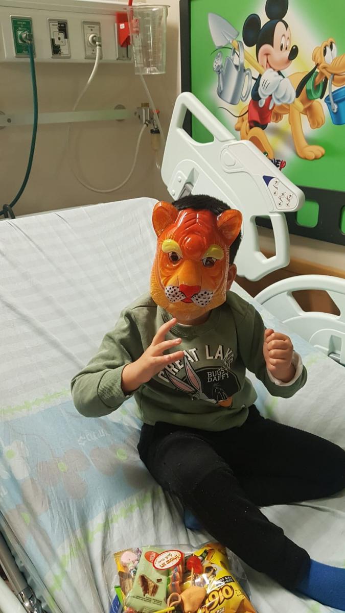 מתחת למסכה מסתתר חיוך גדול. אחד הילדים שזכה לביקור שוטרי היס''מ (צילום: דוברות המשטרה)