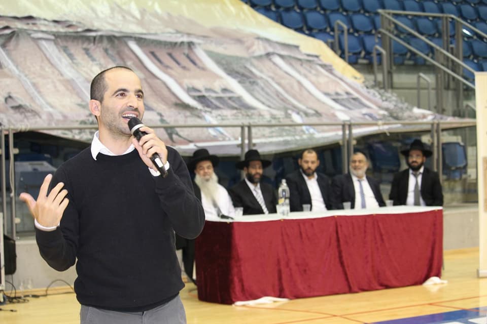 יאיר שושן מנחה את ה'ערב הקדוש' בהיכל הקונכיה, במעמד רבנים (צילום: פייסבוק)