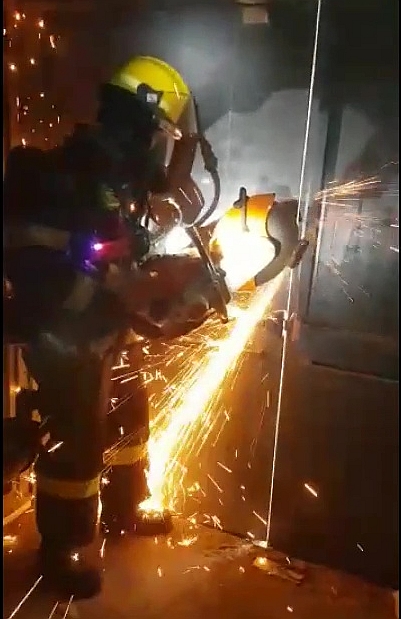 לוחם אש חותך את דלת הכניסה, לאיתור אחר לכודים (צילום: דוברות כבאות והצלה דרום)