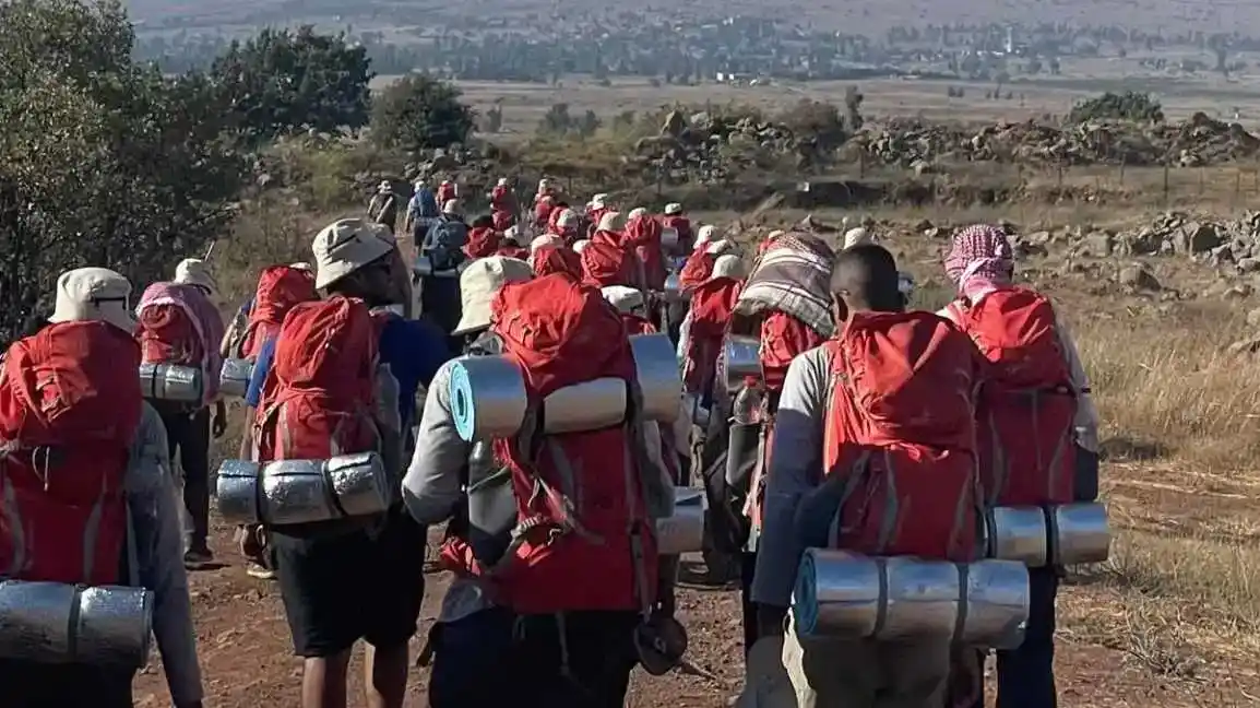 شباب وشابات من البدو يسيرون في صحراء النقب عند الغروب خلال رحلة هويّة