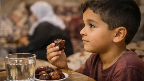 طفل يمسك تمرة بيده منتظراً الأذان بجانب عائلته