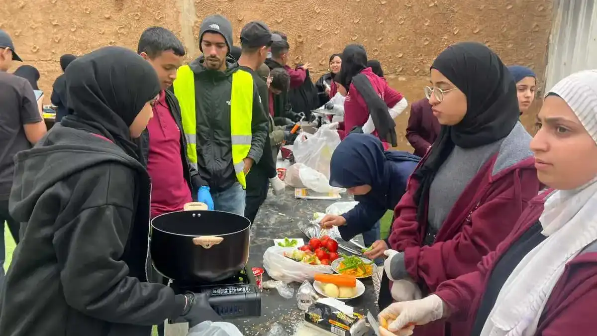 בני נוער בדואים ויהודים עומדים יחד במהלך מסע זהות בנגב, מטיילים ומשוחחים באווירה פתוחה על רקע נופי המדבר.