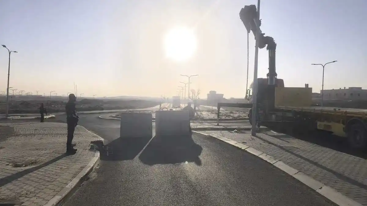 בטונדות בטון גדולות החוסמות כביש בכניסה ליישוב בדואי בנגב, לצד ניידות משטרה וכוחות הפועלים בשטח.