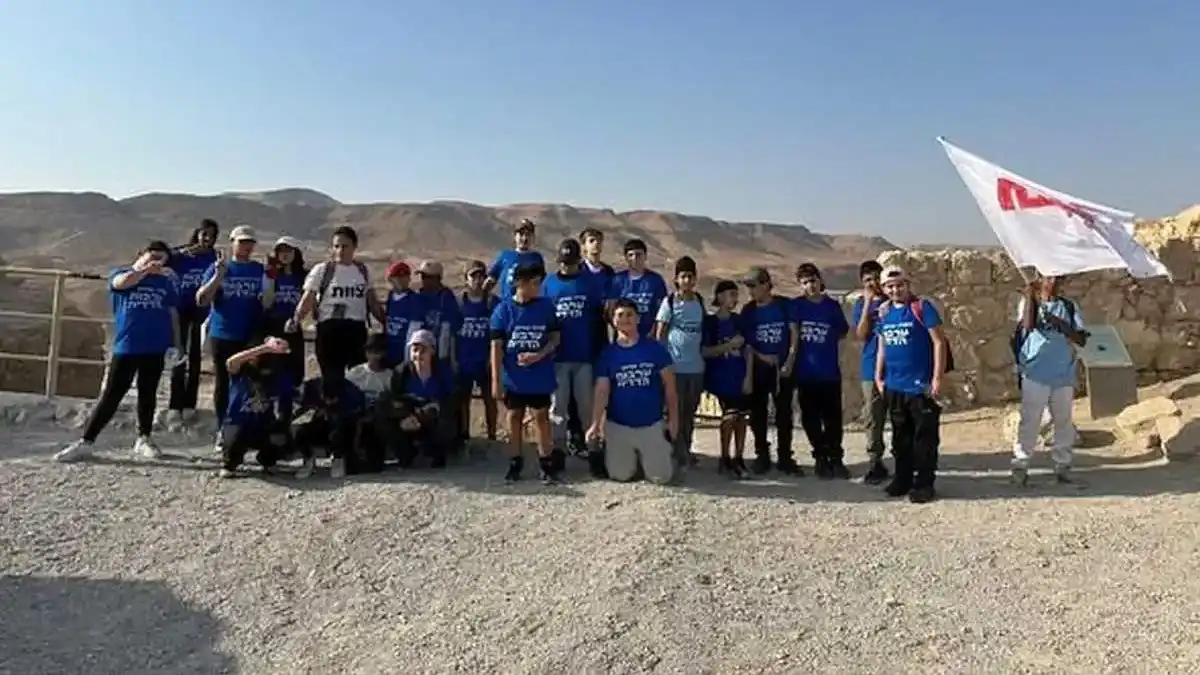 קבוצת תלמידי שכבה ז' עומדת בפסגת מצדה מול הנוף המדברי, במהלך סיור לימודי ערכי מבית ספר דרכא ליהמן בדימונה.