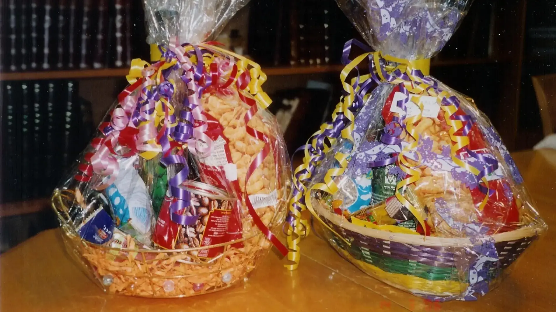 משלוחי מנות מסודרים על שולחן מטבח מודרני, באריזות קראפט נקיות, עם אוזני המן וקינוחים קטנים.