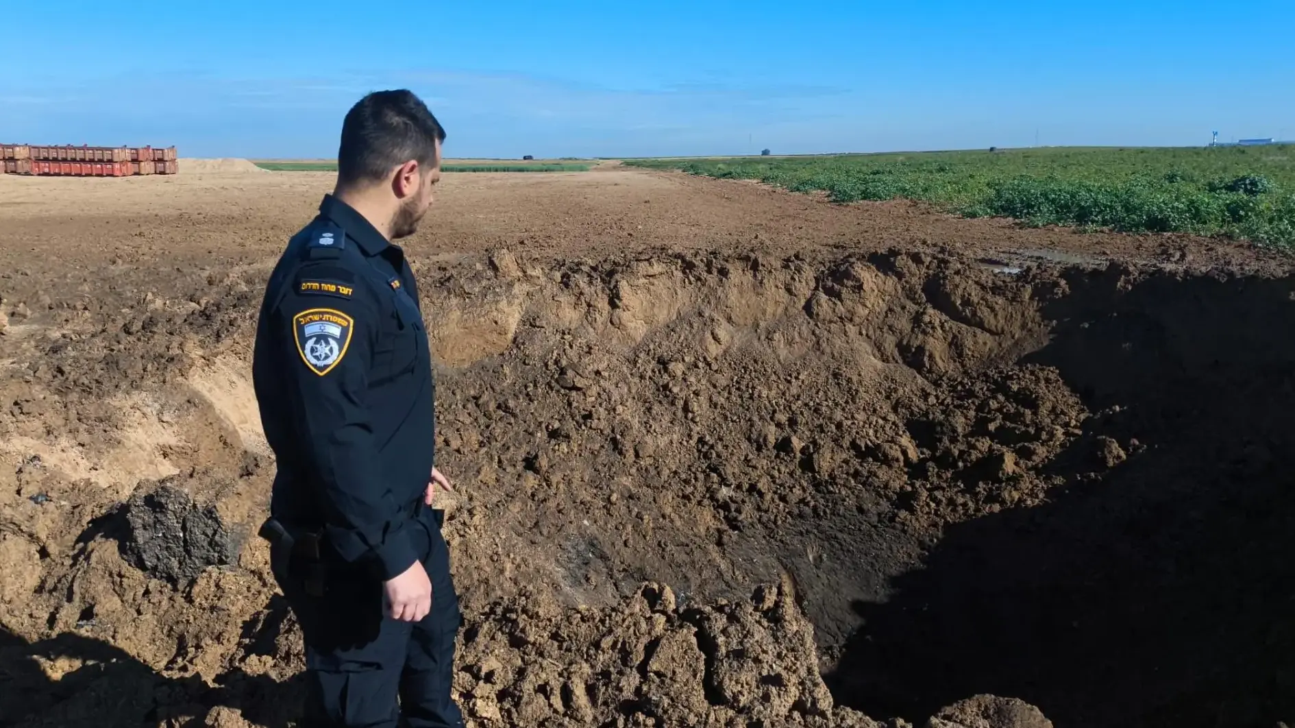 שוטר על שפת מכתש שיצרה פגיעת טיל איראני