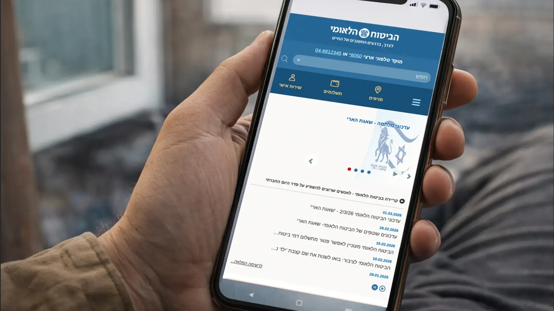 אדם גולש באתר ביטוח לאומי בטלפון נייד ומחפש מידע על זכויות בזמן חירום