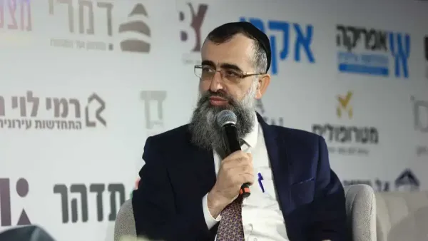 צילום של הרב נתן אלנתן נואם בכנס תכנון ובנייה, לצד מצגת המציגה את רפורמת מורשה להיתר