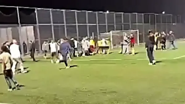 אוהדים פורצים למגרש במהלך משחק ליגה ג' בין כסייפה למ.ס באר שבע, כאשר שחקנים ואנשי צוות מנסים להתרחק מהמהומה.