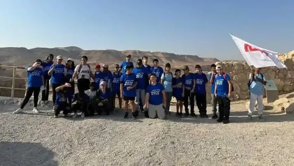 קבוצת תלמידי שכבה ז' עומדת בפסגת מצדה מול הנוף המדברי, במהלך סיור לימודי ערכי מבית ספר דרכא ליהמן בדימונה.