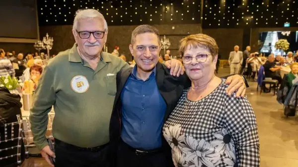 קהל ותיקים יושב באולם אירועים מקושט בבאר שבע במהלך חגיגת יום הולדת 80 עירונית.