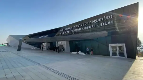 מבט על מסלול נמל התעופה רמון באזור הערבה, עם מגדל פיקוח ומטוס על הקרקע, על רקע שטח מדברי פתוח.