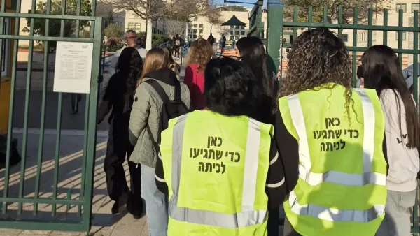 הורים מתנדבים מסיירת ההורים של תיכון רגר מקבלים את פני התלמידים בשער בית הספר