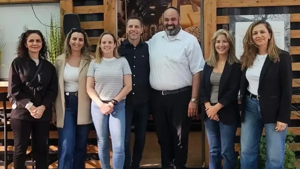 מבקרים בפסטיבל בדרום עם דוכנים מקומיים ופריחות אדומות ברקע