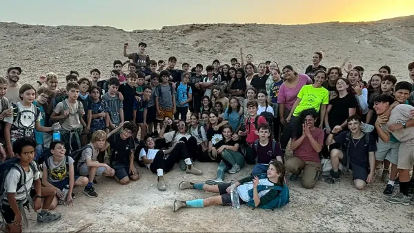 מורים ותלמידים בבית ספר ברמת הנגב על רקע נוף מדברי ויישוב קהילתי בדרום