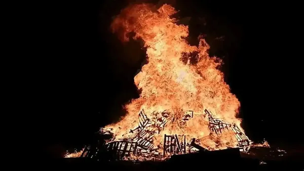 מדורת ל"ג בעומר גדולה בשטח פתוח בבאר שבע עם משפחות חוגגות סביב האש בלילה.