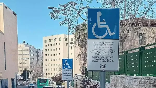 חניית נכים לצד טלפון נייד עם אפליקציית 'חניתי' של משרד התחבורה.