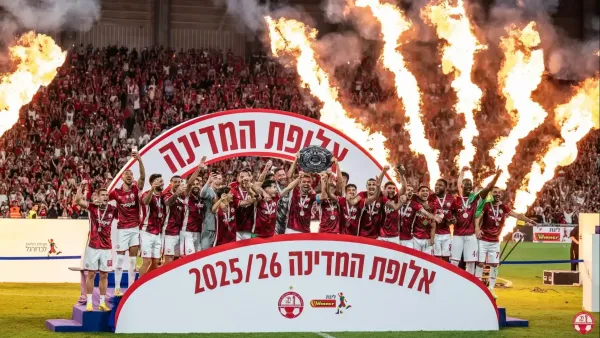 אלפי אוהדי הפועל באר שבע חוגגים אליפות בפארק נחל באר שבע עם דגלים אדומים וצלחת האליפות.