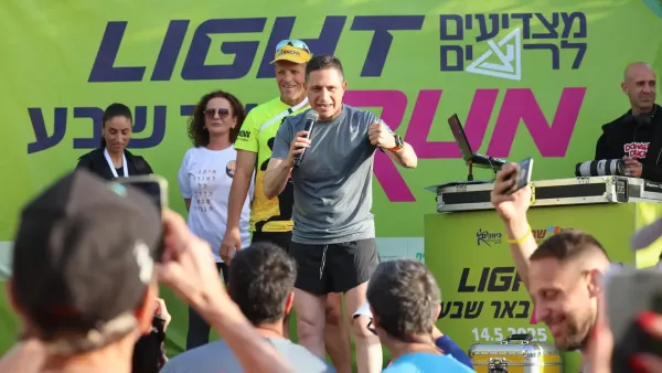 רצים משתתפים במרוץ הלילה של באר שבע בפארק נחל באר שבע, על רקע תאורה צבעונית ואווירת פסטיבל.
