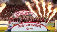 אלפי אוהדי הפועל באר שבע חוגגים אליפות בפארק נחל באר שבע עם דגלים אדומים וצלחת האליפות.