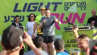 רצים משתתפים במרוץ הלילה של באר שבע בפארק נחל באר שבע, על רקע תאורה צבעונית ואווירת פסטיבל.